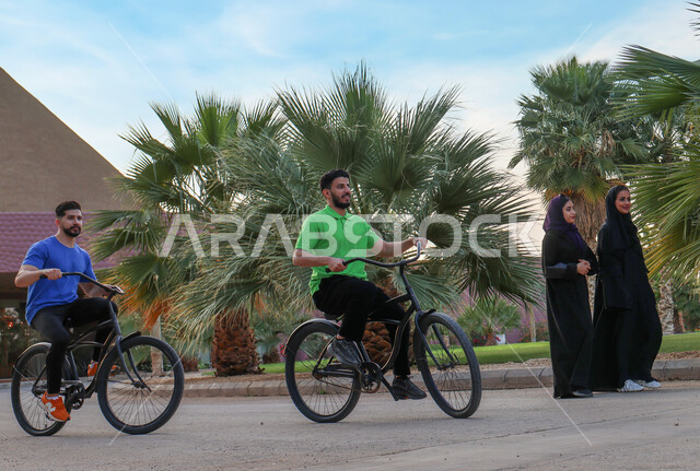 صديقان عربيان خليجيان سعوديان يقودان الدراجه الهوائيه في احد الحدائق العامة، ممارسة هواية ركوب الدراجات، أنشطة ترفيهيه، عطلة صيفية، أماكن عامة, ركوب الدراجات في الهواء الطلق