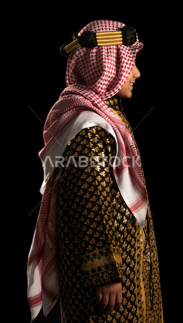 صورة جانبية لولد عربي خليجي سعودي يرتدي زي تراثي سعودي للمناسبات الوطنية والاحتفالية، تاسيس المملكة العربية السعودية، ذكرى اليوم الوطني السعودي، زي سعودي شعبي، يوم التأسيس السعودي، العيد الوطني السعودي، بورتريه، خلفية سوداء
