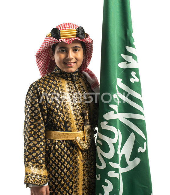 بورتريه لولد عربي خليجي سعودي، بجانب علم السعودية، إرتداء الزي السعودي الشعبي التقليدي، الإحتفالات الوطنية في المنطقة الوسطى، هوية اليوم الوطني السعودي 92، خلفية بيضاء، يوم التأسيس السعودي، زي تراثي سعودي للمناسبات الوطنية، العيد الوطني السعودي