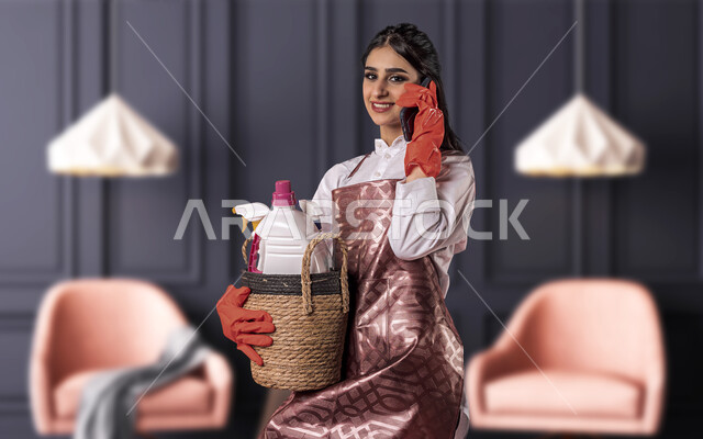 عاملة نظافة تجري مكالمة هاتفية، استخدام الهاتف المحمول، النظافة والتطهير، ادوات ومعدات التنظيف، قفازات اليدين، سلة ادوات التنظيف المنزلية، مدبرة منزلية، خادمة منزلية اجنبية، التنظيف وحماية المنزل