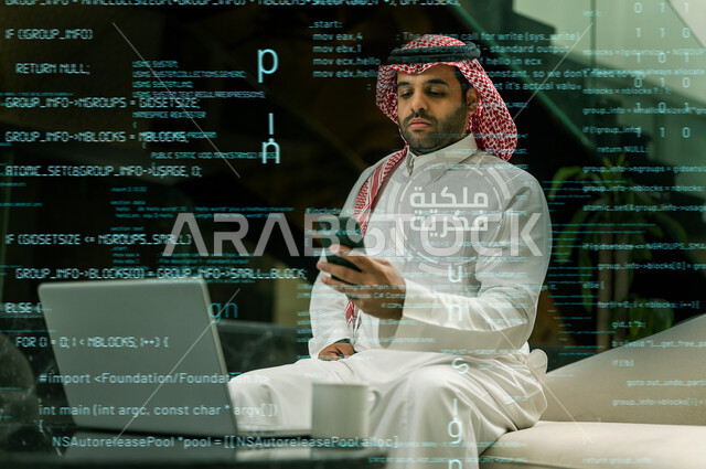 رجل عربي خليجي سعودي يستخدم جهاز الحاسوب المحمول لتطوير شبكة الحاسوب والانظمة البرمجية ، العمل عن بعد ، تكنولوجيا المعلومات ، خلفية هولوجرام ثلاثية الابعاد