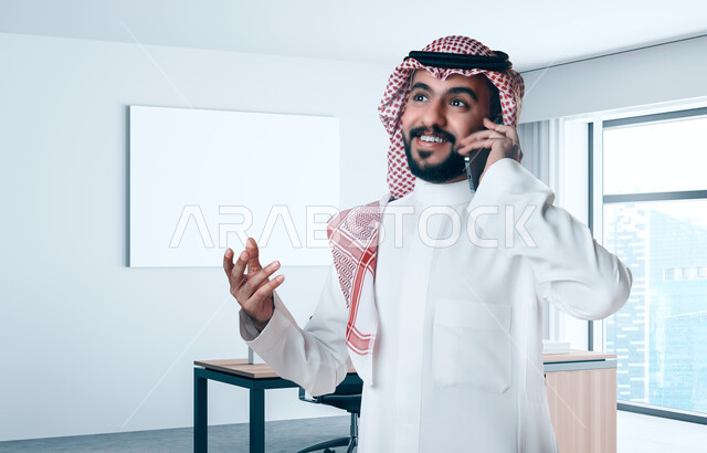 رجل عربي خليجي سعودي يقوم بإجراء مكالمة هاتفية، استخدام الهاتف المحمول، مفهوم إدارة الأعمال، عقد صفقات تجارية، العمل عن بعد، التسويق الإلكتروني، مكالمة خاصة بالعمل، اتصال وتواصل اجتماعي، متابعة العمل، اعمال مكتبية