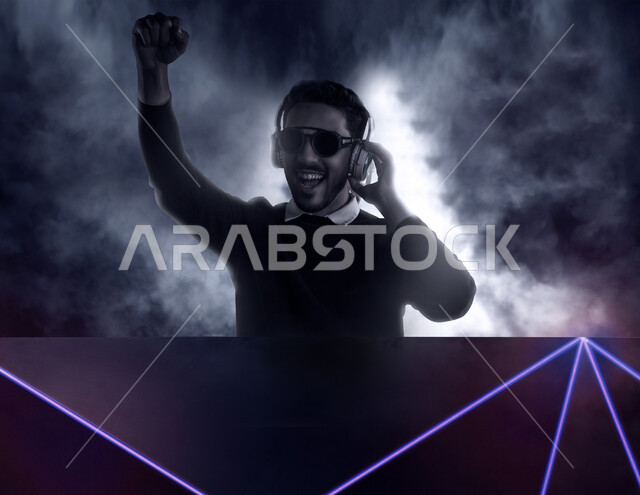 رجل عربي خليجي سعودي يضع سماعة رأس ويرتدي نظارة سوداء، ايماءات وجه و يدين تدل على السعادة والاستمتاع، موهبة الغناء، حفلات موسيقية، خلفية ضبابية