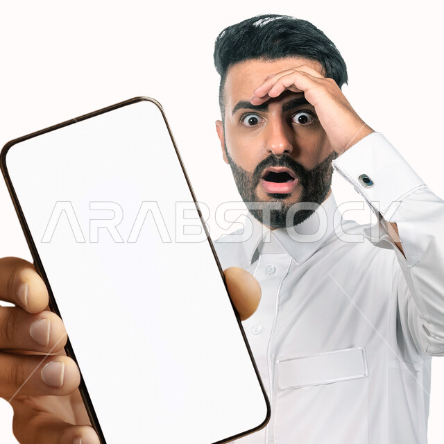 بورتريه لشاب عربي خليجي سعودي يقوم بعرض جهاز الهاتف المحمول بإيماءات مختلفة ، الحصول على الهدف المراد ، التسويق الرقمي ، اعلانات تسويقية ترويجية ، تطبيقات الهاتف الذكي , استخدام التقنية الحديثة , خلفية بيضاء .