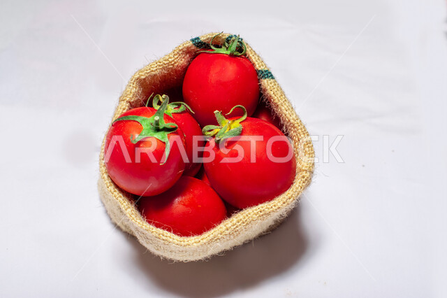 أكياس خيش من الطماطم ( البندورة )  ، مزروعات من الخضار الطازجة ، طماطم مصنوعة من البلاستيك , خلفية بيضاء . 