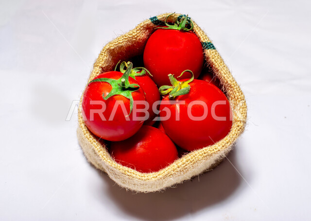 أكياس خيش من الطماطم ( البندورة )  ، مزروعات من الخضار الطازجة ، طماطم مصنوعة من البلاستيك , خلفية بيضاء . 