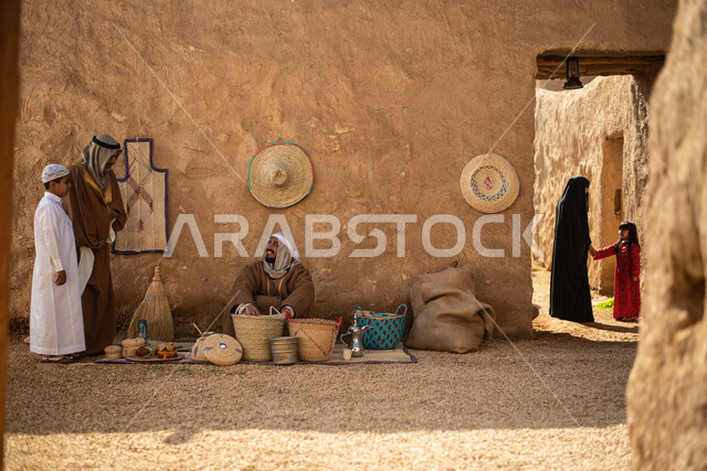 مجموعة من الأشخاص داخل سوق شعبي قديم، أعمال وصناعات يدوية، احياء التراث الشعبي الخليجي، مهن وحرف يدوية شعبية، يوم التأسيس السعودي، تأسيس المملكة 1727م ، أزياء شعبية سعودية، السعودية القديمة، بيوت طينية تراثية قديمة