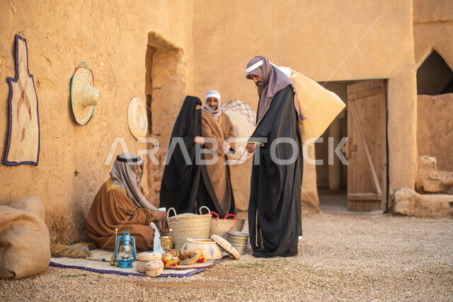 مجموعة من الأشخاص داخل سوق شعبي قديم، أعمال وصناعات يدوية، احياء التراث الشعبي الخليجي، مهن وحرف يدوية شعبية، يوم التأسيس السعودي، تأسيس المملكة 1727م ، أزياء شعبية سعودية، السعودية القديمة، بيوت طينية تراثية قديمة