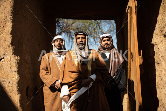مجموعة من الرجال العرب السعوديون، يوم التأسيس السعودي، تأسيس المملكة 1727م ، أزياء شعبية سعودية، السعودية القديمة، بيوت طينية تراثية قديمة، زي تراثي سعودي للمناسبات الوطنية
