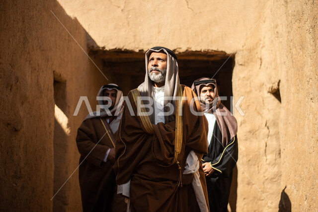 مجموعة من الرجال العرب السعوديون، يوم التأسيس السعودي، تأسيس المملكة 1727م ، أزياء شعبية سعودية، السعودية القديمة، بيوت طينية تراثية قديمة، زي تراثي سعودي للمناسبات الوطنية