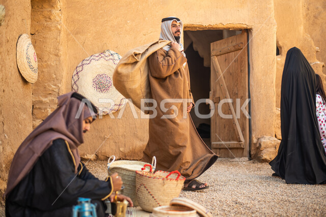 مجموعة من الأشخاص داخل سوق شعبي قديم، أعمال وصناعات يدوية، احياء التراث الشعبي الخليجي، مهن وحرف يدوية شعبية، يوم التأسيس السعودي، تأسيس المملكة 1727م ، أزياء شعبية سعودية، السعودية القديمة، بيوت طينية تراثية قديمة