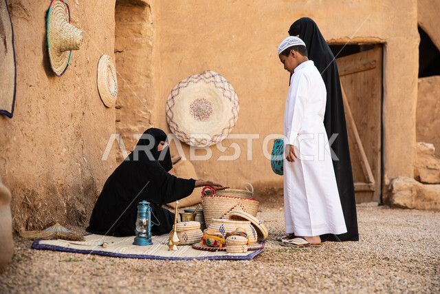مجموعة من الأشخاص داخل سوق شعبي قديم، أعمال وصناعات يدوية، احياء التراث الشعبي الخليجي، مهن وحرف يدوية شعبية، يوم التأسيس السعودي، تأسيس المملكة 1727م ، أزياء شعبية سعودية، السعودية القديمة، بيوت طينية تراثية قديمة