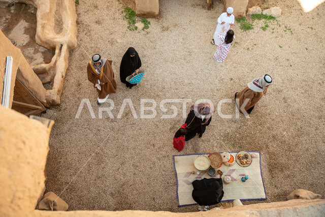 A group of people inside an old popular market, handicrafts and works, revival of Gulf folklore, popular handicrafts and professions, Saudi founding day, the founding of the Kingdom 1727 AD, Saudi folk costumes, old Saudi Arabia, old traditional mud house
