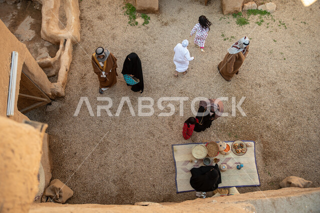 A group of people inside an old popular market, handicrafts and works, revival of Gulf folklore, popular handicrafts and professions, Saudi founding day, the founding of the Kingdom 1727 AD, Saudi folk costumes, old Saudi Arabia, old traditional mud house