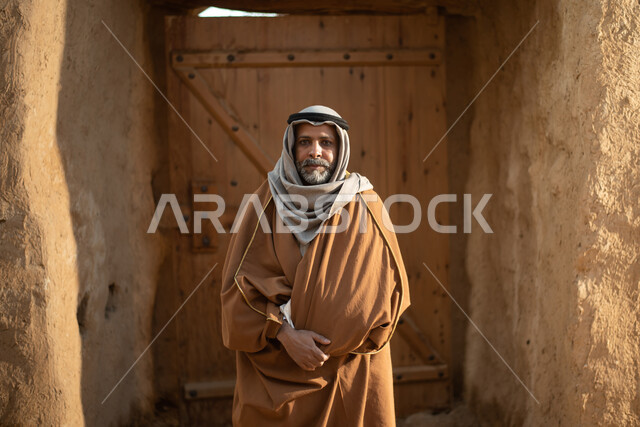 رجل عربي خليجي سعودي كبير السن، يوم التأسيس السعودي، تأسيس المملكة 1727م ، أزياء شعبية سعودية، السعودية القديمة، بيوت طينية تراثية قديمة، زي تراثي سعودي للمناسبات الوطنية