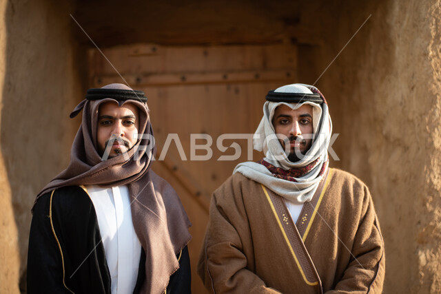 Two Saudi Arabian Gulf men, Saudi founding day, the founding of the Kingdom 1727 AD, Saudi folk costumes, old Saudi Arabia, old traditional mud houses, Saudi traditional costume for national occasions