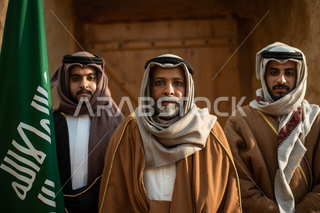 مجموعة من الرجال العرب السعوديون، علم المملكة العربية السعودية، يوم التأسيس السعودي، تأسيس المملكة 1727م ، أزياء شعبية سعودية، السعودية القديمة، بيوت طينية تراثية قديمة، زي تراثي سعودي للمناسبات الوطنية