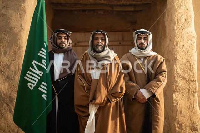 A group of Saudi Arab men, the flag of the Kingdom of Saudi Arabia, the Saudi founding day, the founding of the Kingdom in 1727 AD, Saudi folk costumes, old Saudi Arabia, old traditional mud houses, Saudi traditional costume for national occasions