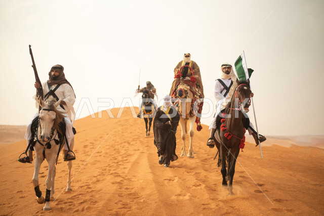 فارسان عربيان خلجيان سعوديان يمتطيان الخيول في الصحراء السعودية، استخدام البندقية السعودية، رفع العلم السعودي، ارتداء ازياء شعبية تراثية، رجل ملثم يركب الجمل، احياء ذكرى التاسيس السعودي، الدولة السعودية الاولى 1727م، يوم التاسيس السعودي، عيد وطني سعودي