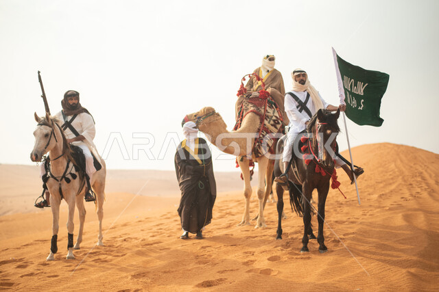 فارسان عربيان خلجيان سعوديان يمتطيان الخيول في الصحراء السعودية، استخدام البندقية السعودية، رفع العلم السعودي، ارتداء ازياء شعبية تراثية، رجل ملثم يركب الجمل، احياء ذكرى التاسيس السعودي، الدولة السعودية الاولى 1727م، يوم التاسيس السعودي، عيد وطني سعودي