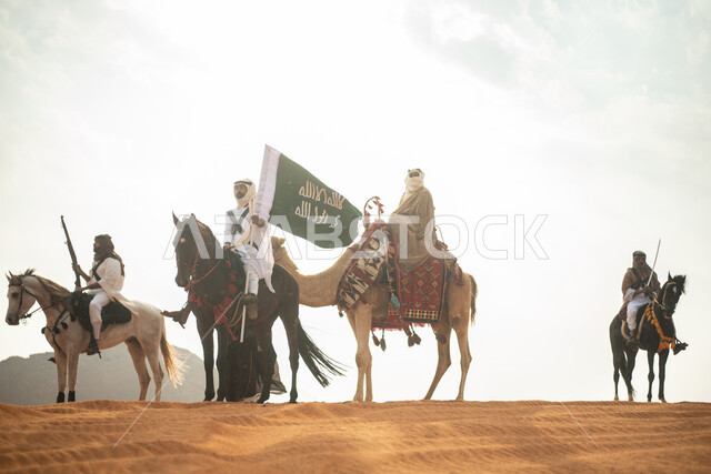 فارسان عربيان خلجيان سعوديان يمتطيان الخيول في الصحراء السعودية، استخدام البندقية السعودية، رفع العلم السعودي، ارتداء ازياء شعبية تراثية، رجل ملثم يركب الجمل، احياء ذكرى التاسيس السعودي، الدولة السعودية الاولى 1727م، يوم التاسيس السعودي، عيد وطني سعودي