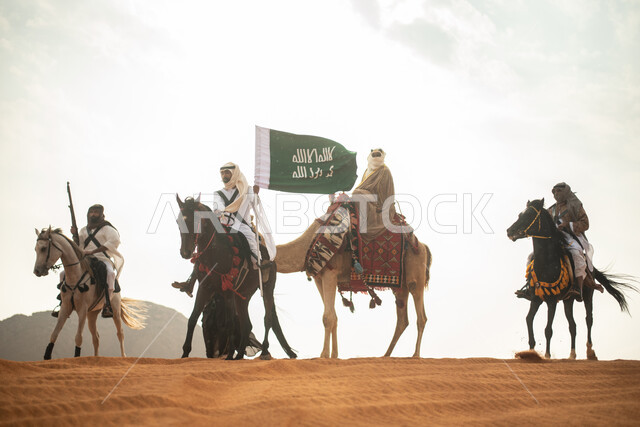 فارسان عربيان خلجيان سعوديان يمتطيان الخيول في الصحراء السعودية، استخدام البندقية السعودية، رفع العلم السعودي، ارتداء ازياء شعبية تراثية، رجل ملثم يركب الجمل، احياء ذكرى التاسيس السعودي، الدولة السعودية الاولى 1727م، يوم التاسيس السعودي، عيد وطني سعودي