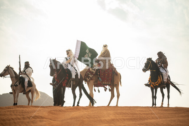 فارسان عربيان خلجيان سعوديان يمتطيان الخيول في الصحراء السعودية، استخدام البندقية السعودية، رفع العلم السعودي، ارتداء ازياء شعبية تراثية، رجل ملثم يركب الجمل، احياء ذكرى التاسيس السعودي، الدولة السعودية الاولى 1727م، يوم التاسيس السعودي، عيد وطني سعودي