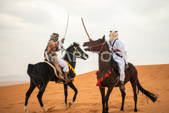 فارسان عربيان خليجيان سعوديان يمتطيان الخيل في الصحراء السعودية ويتبارزان، مبارزة السيوف، ارتداء زي تراثي شعبي، احياء ذكرى التاسيس السعودي، الدولة السعودية الاولى 1727م، يوم التاسيس السعودي، عيد وطني سعودي