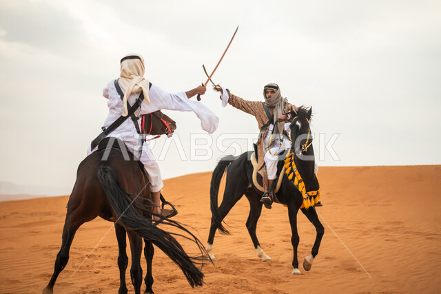 فارسان عربيان خليجيان سعوديان يمتطيان الخيل في الصحراء السعودية ويتبارزان، مبارزة السيوف، ارتداء زي تراثي شعبي، احياء ذكرى التاسيس السعودي، الدولة السعودية الاولى 1727م، يوم التاسيس السعودي، عيد وطني سعودي