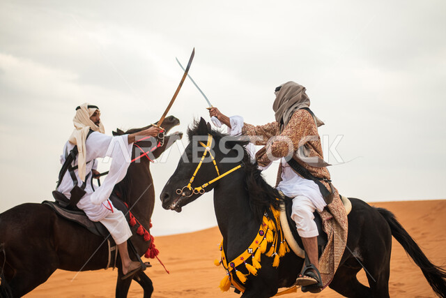 فارسان عربيان خليجيان سعوديان يمتطيان الخيل في الصحراء السعودية ويتبارزان، مبارزة السيوف، ارتداء زي تراثي شعبي، احياء ذكرى التاسيس السعودي، الدولة السعودية الاولى 1727م، يوم التاسيس السعودي، عيد وطني سعودي