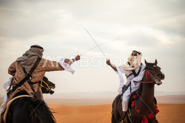 فارسان عربيان خليجيان سعوديان يمتطيان الخيل في الصحراء السعودية ويتبارزان، مبارزة السيوف، ارتداء زي تراثي شعبي، احياء ذكرى التاسيس السعودي، الدولة السعودية الاولى 1727م، يوم التاسيس السعودي، عيد وطني سعودي