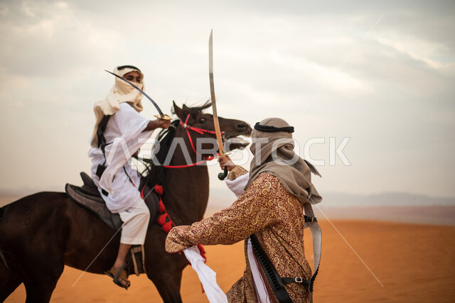 فارسان عربيان خليجيان سعوديان يمتطيان الخيل في الصحراء السعودية ويتبارزان، مبارزة السيوف، ارتداء زي تراثي شعبي، احياء ذكرى التاسيس السعودي، الدولة السعودية الاولى 1727م، يوم التاسيس السعودي، عيد وطني سعودي