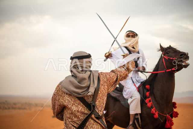 فارسان عربيان خليجيان سعوديان يمتطيان الخيل في الصحراء السعودية ويتبارزان، مبارزة السيوف، ارتداء زي تراثي شعبي، احياء ذكرى التاسيس السعودي، الدولة السعودية الاولى 1727م، يوم التاسيس السعودي، عيد وطني سعودي