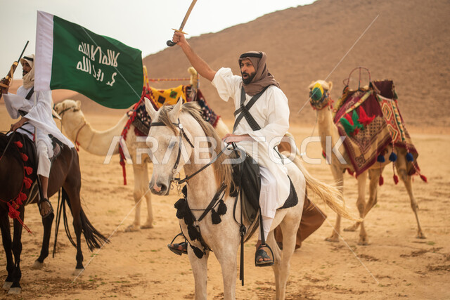 فرسان عرب خلجيين سعوديين يمتطون الخيول في الصحراء السعودية، استخدام السيوف والبنادق، رفع العلم السعودي، ارتداء ازياء شعبية تراثية، احياء ذكرى التاسيس السعودي، الدولة السعودية الاولى 1727م، يوم التاسيس السعودي، عيد وطني سعودي