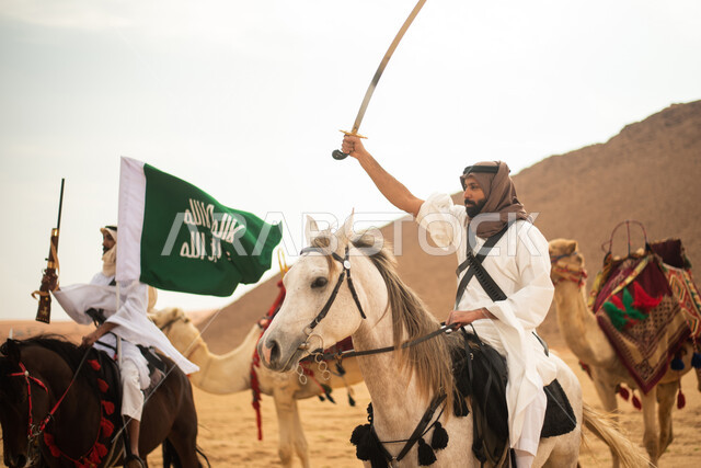 Saudi Gulf Arab knights riding horses in the Saudi desert, using swords and guns, raising the Saudi flag, wearing traditional folk costumes, commemorating the Saudi founding, the first Saudi state 1727 AD, Saudi founding day, Saudi national holiday