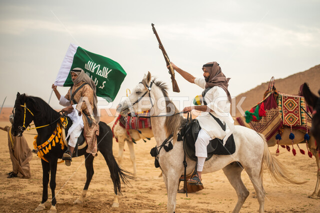 فرسان عرب خلجيين سعوديين يمتطون الخيول في الصحراء السعودية، استخدام السيوف والبنادق، رفع العلم السعودي، ارتداء ازياء شعبية تراثية، احياء ذكرى التاسيس السعودي، الدولة السعودية الاولى 1727م، يوم التاسيس السعودي، عيد وطني سعودي