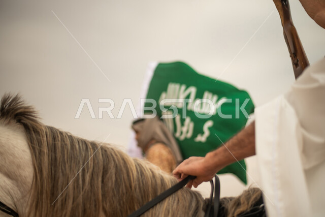 Saudi Gulf Arab knights riding horses in the Saudi desert, using the Saudi rifle, raising the Saudi flag, wearing traditional folk costumes, commemorating the Saudi founding, the first Saudi state 1727 AD, Saudi founding day, Saudi national holiday