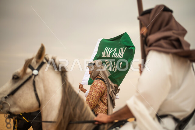 فرسان عرب خلجيين سعوديين يمتطون الخيول في الصحراء السعودية، استخدام البندقية السعودية، رفع العلم السعودي، ارتداء ازياء شعبية تراثية، احياء ذكرى التاسيس السعودي، الدولة السعودية الاولى 1727م، يوم التاسيس السعودي، عيد وطني سعودي