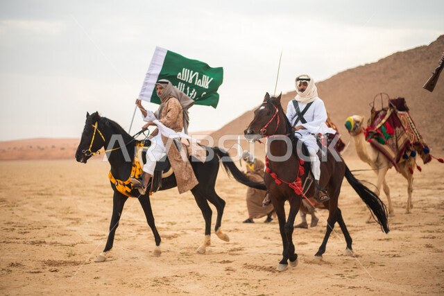 فرسان عرب خلجيين سعوديين يمتطون الخيول في الصحراء السعودية، استخدام السيوف والبنادق، رفع العلم السعودي، ارتداء ازياء شعبية تراثية، احياء ذكرى التاسيس السعودي، الدولة السعودية الاولى 1727م، يوم التاسيس السعودي، عيد وطني سعودي