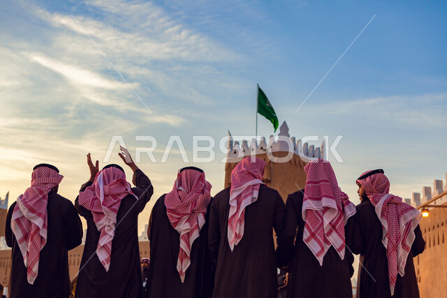 Photography from the back of a group of Saudi Arab Gulf men, the Saudi flag, the commemoration of the Saudi founding day, the Saudi National Day, the Saudi National Day