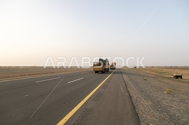 عبور الناقلات الثقيلة على الطريق السريع في النهار  ، وسائل المواصلات ، الطبيعة الصحراوية بالمملكة العربية السعودية ، طريق اسفلتي للعبور .