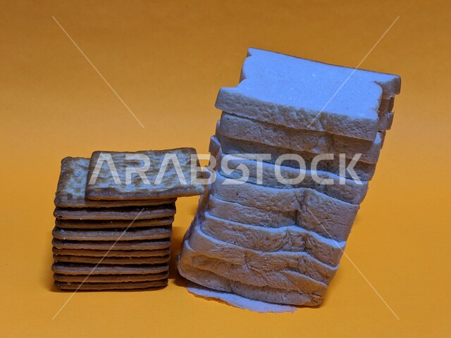 Sliced white toast bread and biscuits on a yellow background, baked goods