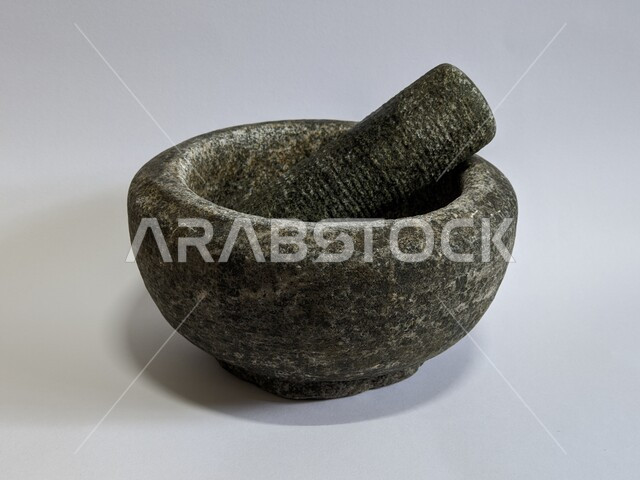 هاون الحجر الجرانيت ومدقة على خلفية بيضاء ، أدوات تقليدي قديمة ، الطحن اليدوي