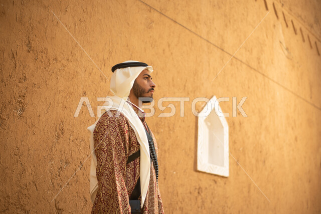 A side image of a Saudi Arabian Gulf man wearing a traditional costume for national and festive occasions, a popular Saudi costume, commemorating the Saudi founding day, the establishment of the first Saudi state in 1727 AD, the background of ancient anci