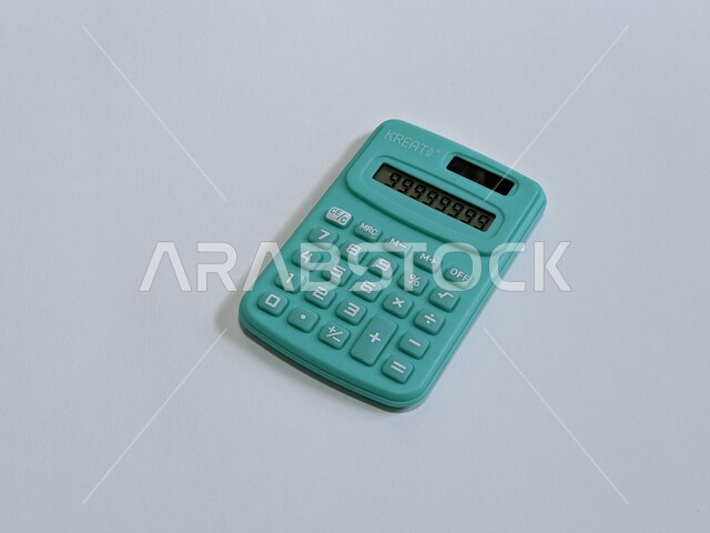 Blue small calculator on a white background, performing arithmetic operations, stationery