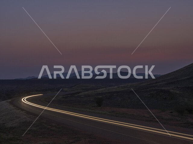 لقطة سريعة لحركة مرور السيارات بجانب المرتفعات الجبلية في المملكة العربية السعودية ، حركة سير السيارات على الطريق ، جمال الغروب طرق و شوارع المدينة ليلاً .