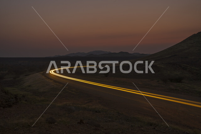 لقطة سريعة لحركة مرور السيارات بجانب المرتفعات الجبلية في المملكة العربية السعودية ، حركة سير السيارات على الطريق ، جمال الغروب طرق و شوارع المدينة ليلاً .