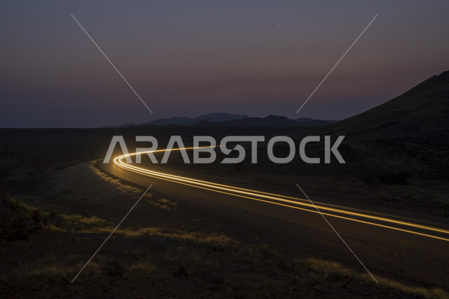 لقطة سريعة لحركة مرور السيارات بجانب المرتفعات الجبلية في المملكة العربية السعودية ، حركة سير السيارات على الطريق ، جمال الغروب طرق و شوارع المدينة ليلاً .
