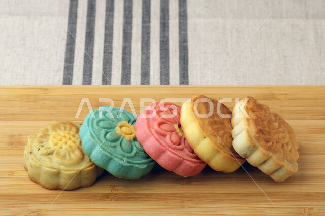 معمول التمر ملون مربع الشكل ، الحلويات الشعبية الهشة على لوح خشبي ، كعك العيد 