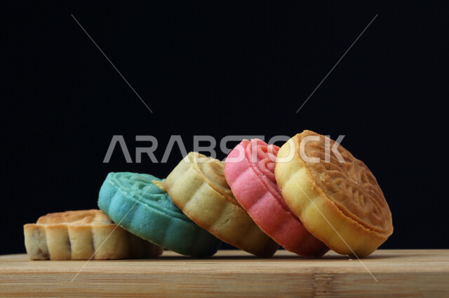 معمول التمر ملون مربع الشكل ، الحلويات الشعبية الهشة على لوح خشبي ، كعك العيد 